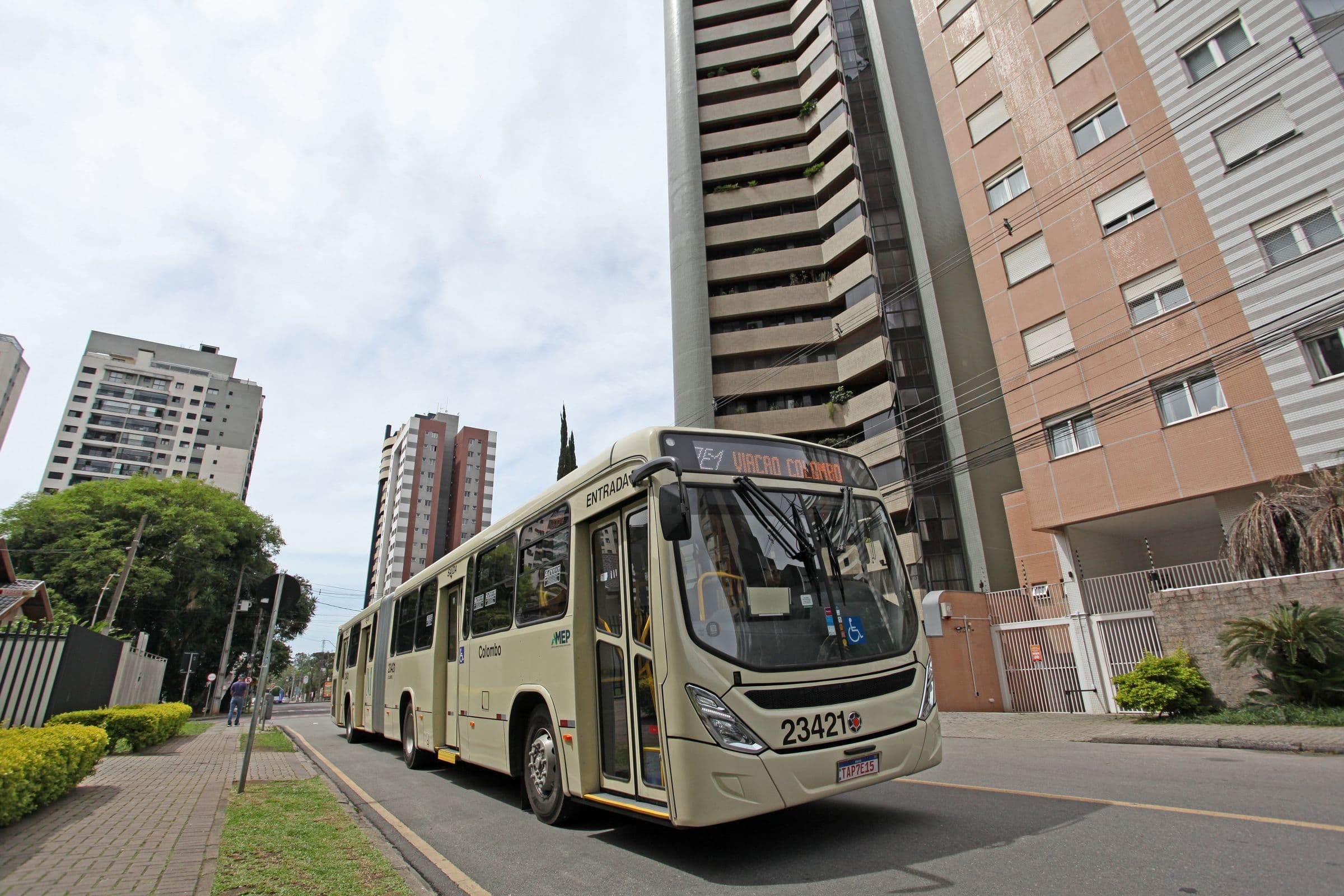 Ônibus articulado numa avenida de Curitiba, entre prédios altos