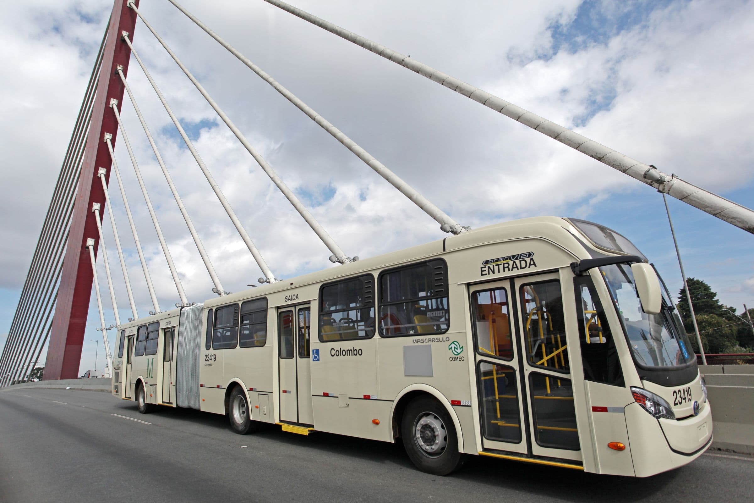 Ônibus articulado passando sob um viaduto estaiado