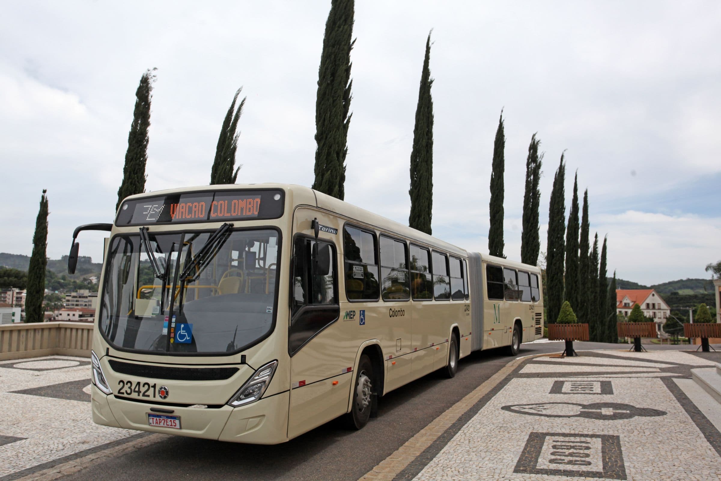 Ônibus articulado na praça da Igreja Matriz de Colombo, entre ciprestes