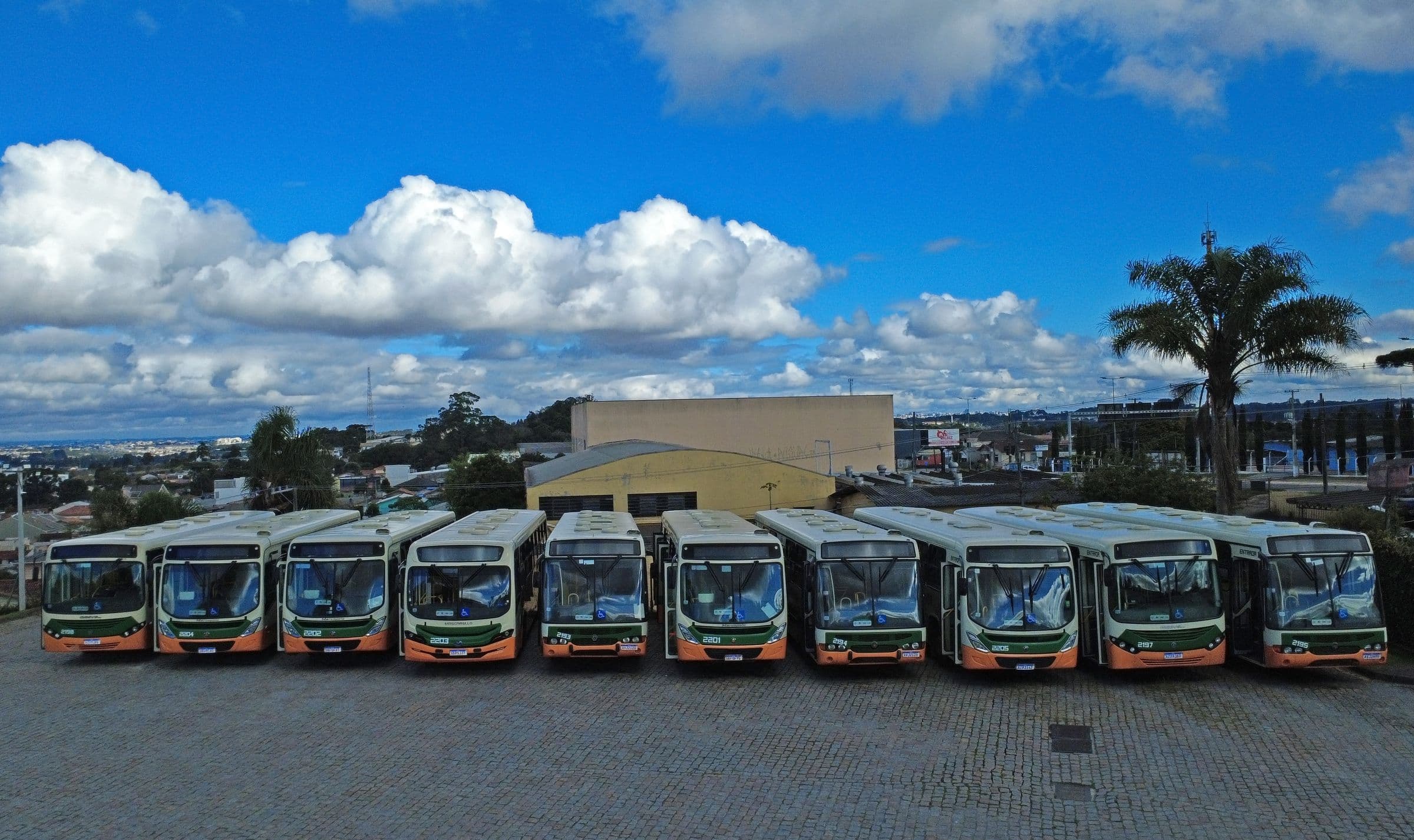 Ônibus da Viação Colombo enfileirados no pátio, vistos de frente